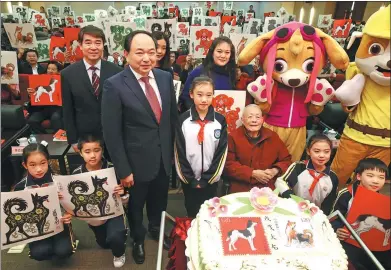  ?? JIANG DONG / CHINA DAILY ?? Zhou Lingzhao (middle in red), 99, attends a ceremony in Beijing to issue the Year of the Dog stamps he designs. A cake to mark the release bears the stamps’ patterns.