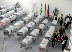  ??  ?? Funeral workers in Medellin, Colombia prepare the victims’ coffins to be flown to Bolivia and Brazil.