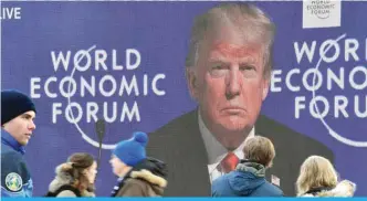  ??  ?? DAVOS: People pass in front of big screen during the speech of US President Donald Trump on January 26, 2018 at the Davos Congress Centre (C), the venue of the annual World Economic Forum.—AFP