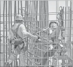  ??  ?? Constructi­on workers working with steel rebar during the constructi­on of a building. — AFP photo