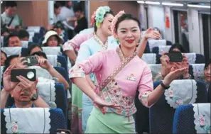  ?? WANG JINGYI / XINHUA ?? Crew members perform for passengers on Saturday onboard a train running from Xishuangba­nna Dai autonomous prefecture in Yunnan province to Luang Prabang in Laos.