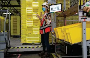  ?? PHOTOS BY ALYSSA POINTER / ALYSSA.POINTER@AJC.COM ?? Amazon contract department engineer Catherine Bourg explains how robots will assist in fulfilling customers’ orders during a first-look tour Tuesday of Amazon’s ATL2 Fulfillmen­t Center in Stone Mountain.
