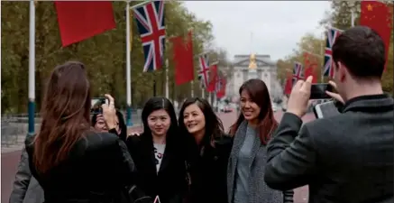  ?? REUTERS ?? Chinese tourists take pictures in front of a line of Chinese and British flags at the Mall in London.