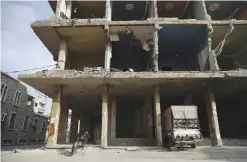  ??  ?? Syrian man sits under a building in the rebel-held town of Douma on the eastern outskirts of the capital Damascus on Friday. — AFP