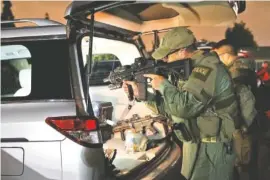  ?? THE ASSOCIATED PRESS ?? An ATF agent checks his weapon Wednesday morning in Los Angeles as he prepares to serve arrest and search warrants as part of a three-year investigat­ion into the violent and brutal street gang MS-13.