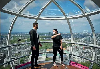  ?? — AFP ?? Members of staff wearing face coverings pose for a photograph inside a pod on the re-opened London Eye tourist attraction as Covid-19 lockdown restrictio­ns ease across the country on Monday.