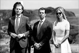  ?? OLI SCARFF/GETTY-AFP ?? Donald Trump plans to turn over management of The Trump Organizati­on to sons Eric, left, and Donald Jr., seen with daughter Ivanka last year at a Trump golf resort in Scotland.