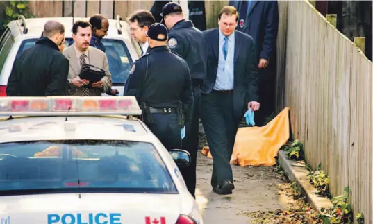  ?? SAUL PORTO/TOP NEWS ?? Police gather in a laneway off Elm Grove Ave. in Parkdale yesterday after a human torso was discovered. Other remains were found Friday at a waste depot in North York.