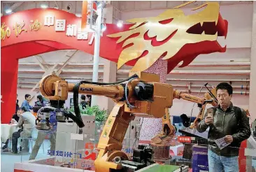  ?? [AP FILE PHOTO] ?? Visitors look at industrial robots displayed beneath the words that read “Chinese Robots” during the World Robot Conference in Beijing. U.S. officials have a name for their frustratio­n with Beijing’s technology ambitions: “Made in China 2025.”...