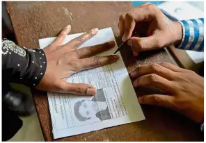  ??  ?? Doing her duty: An election official putting indelible ink on the finger of a voter at a polling station in Bangalore.