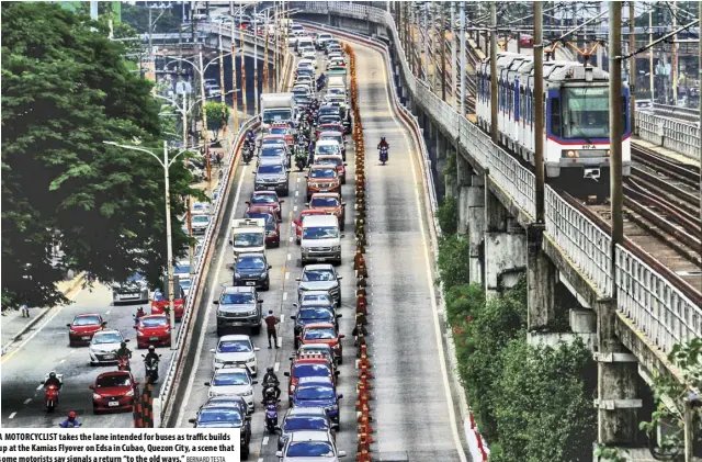  ?? BERNARD TESTA ?? A MOTORCYCLI­ST takes the lane intended for buses as traffic builds up at the Kamias Flyover on Edsa in Cubao, Quezon City, a scene that some motorists say signals a return “to the old ways.”