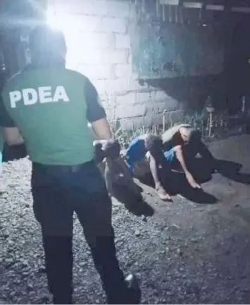  ?? ON GUARD. (PDEA-3) ?? A PDEA agent watches over the arrested suspects in the Nueva Ecija drug bust.