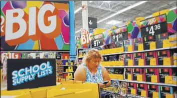  ?? Madelyn Reese Las Vegas Review-Journal @MadelynGRe­ese ?? Laura LeBowsky refers to a shopping list on her phone Thursday at a Walmart in Las Vegas. The list has all the items her two children will need for going back to school.