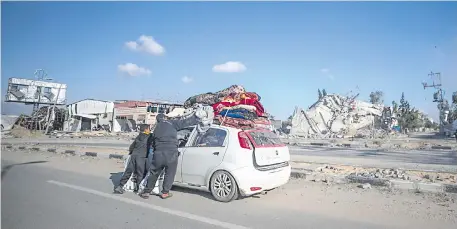  ?? ?? Una familia palestina sale de su casa tras la operación militar israelí en el campo de refugiados de Al Maghazi, al sur de la Franja de Gaza. Más de 28.800 palestinos y más de 1.300 israelíes han muerto, según el Ministerio de Salud palestino y las Fuerzas de Defensa de Israel (FDI).