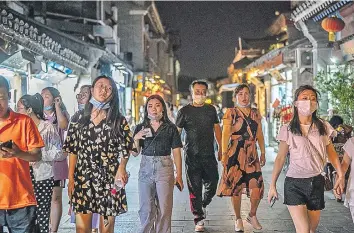  ??  ?? Habitantes de Pekín caminando en una céntrica calle de esa ciudad, donde se detectó un nuevo brote de covid-19, por lo que las autoridade­s dispusiero­n el confinamie­nto de once barrios.