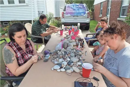  ?? MICHAEL SEARS/MILWAUKEE JOURNAL SENTINEL ?? Crystal Zagorski, left, of Milwaukee is the founder of WI Rocks, which has been working since 2016 to spread joy through painted rocks. Painting with her are her husband, Sam Zagorski, clockwise from top left, their children, Emilio, 11, and Scarlett, 3, and Heather Zunker. They paint inspiratio­nal images and messages on the rocks and place them in urban environmen­ts. Crystal Zagorski has encouraged others to take part in the project through the group’s Facebook page.