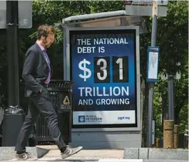  ?? NEW YORK TIMES KENNY HOLSTON/THE ?? A national debt ticker at a bus stop in Washington, D.C., on May 22, 2023.