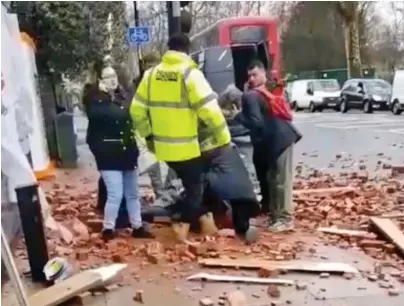  ??  ?? Shock: Passers-by give the woman first aid amid the scattered broken bricks and wood