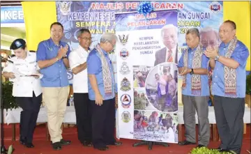  ??  ?? Masing (fourth left) unveils the banner on the river safety campaign, as Murni (second right) and others look on.