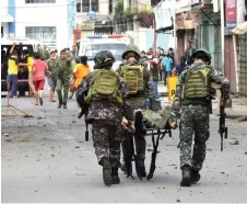  ?? — AFP photo ?? Soldiers stretcher away a comrade after an improvised bomb exploded next to a military vehicle in the town of Jolo on Sulu island.