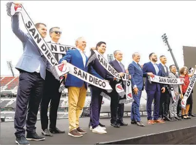  ?? MEG MCLAUGHLIN U-T PHOTOS ?? Owners and affiliates to the new team hold up soccer scarves during the official announceme­nt of the franchise Thursday at Snapdragon Stadium. The team’s colors and crest are still in the works, pending input from the community.