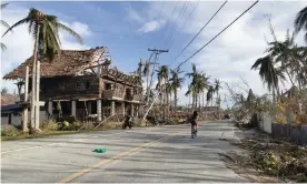  ?? Ferdinandh Cabrera/AFP/Getty Images ?? A cyclist travels past destroyed vegetation and houses along a road in Dapa town, Siargao island on December 21, 2021, days after super Typhoon Rai devastated the island. Photograph: