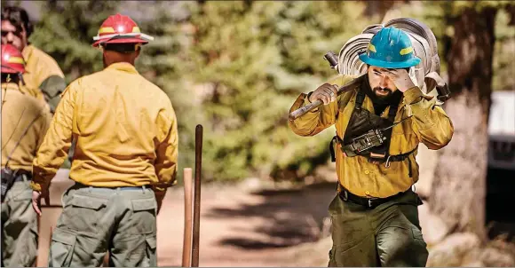  ?? JIM WEBER/New Mexican file photo ?? Firefighte­rs with Structure Group 4 hook up hoses to a sprinkler system to protect homes in a neighborho­od off NM 518 north of the Taos County line from the Hermits Peak–Calf Canyon Fire in May. The House on Tuesday unanimousl­y approved a bill appropriat­ing $100 million to communitie­s devastated by the historic fire.