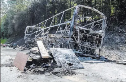  ?? Matthias Balk ?? The Associated Press The charred wreckage of a burnt bus awaits being cleared from the A9 motorway near Muenchberg, Germany, on Monday. Police said 18 seniors on vacation died when the bus crashed into a trailer-truck and burst into flames.