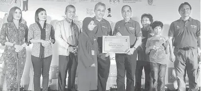  ??  ?? RASMI: Wan Junaidi menerima kad daripada salah seorang kanak-kanak sebagai simbolik perasmian Program Hasanah Bersama Rakyat di Pusat Konvensyen Penview, Kuching semalam.