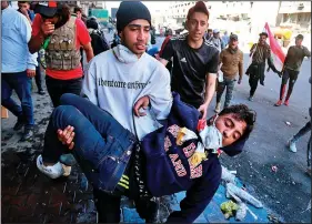  ?? (AP/Hadi Mizban) ?? An injured anti-government protester is rushed to a hospital Monday during clashes with security forces in Baghdad, Iraq.