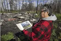  ?? AP FILE ?? Julia Cardinal, a member of the Athabasca Chipewyan First Nation, shows a picture of her riverside cabin destroyed by wildfires.