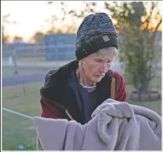  ??  ?? Lou Ann Trahan takes a blanket off a clothes line to stay warm on Christmas Eve, in the gutted home of her daughter.