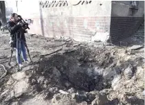  ?? AFP PHOTO ?? BROKE GROUND
A cameraman films a crater next to a college building damaged by a drone attack in the Odesa region, southern Ukraine on Thursday, Feb. 8, 2024.