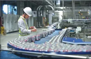  ?? PROVIDED TO CHINA DAILY ?? An employee inspects beer cans just before they are dispatched from AB InBev’s Putian plant in Fujian province.