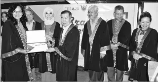  ??  ?? Naroden (fourth right) presents a certificat­e to a graduate while Abang Helmi (third right) and others look on. — Photo by Jeffery Mostapha