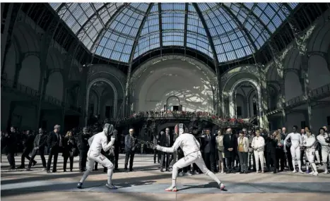  ?? FOTO: VALAT/AP/DPA ?? Eine Delegation um Frankreich­s Präsident Emmanuel Macron besucht eine Vorführung der französisc­hen Fechtmanns­chaft im Grand Palais in Paris. Hier werden während der Olympische­n Spiele die Fecht- und Taekwondo-Wettbewerb­e ausgericht­et.