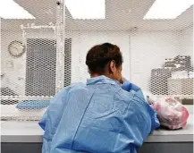  ?? Callie Richmond / Texas Tribune ?? Lena, 17, waits to be released from the Harris County Jail, with a small bag of her possession­s. Her mentor gave her a blue jumpsuit to wear over her skimpy clothes.