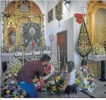  ??  ?? Una niña entrega un ramo de flores al Simpecado de Gines.