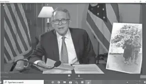  ?? ANNA STAVER/COLUMBUS DISPATCH ?? Ohio Gov. Mike Dewine displays a photograph of his father with a Holocaust survivor during a virtual ceremony on Thursday.