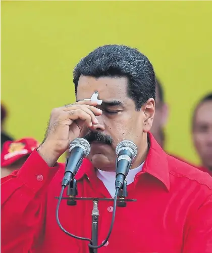  ??  ?? Preocupaci­ón. El presidente venezolano Nicolás Maduro se coloca un crucifijo en la frente ayer en CaracasAP