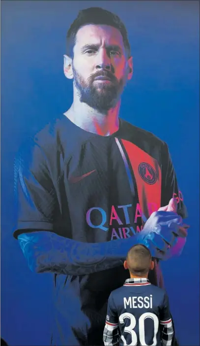  ?? ?? Un niño observa una imagen de Messi en un cartel publicitar­io del PSG.
