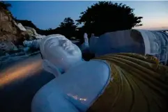  ?? (Reuters) ?? A marble statue of Buddha awaits transporta­tion near the Irrawaddy River