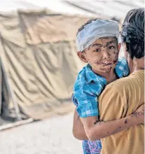  ?? AP PHOTO ?? A boy injured during the tsunami is carried by his relative at a makeshift hospital in Palu, Central Sulawesi, Indonesia on Thursday. People living in tents and shelters have little but uncertaint­y since the powerful earthquake and tsunami hit the city, where death toll rises and efforts to retrieve scores more victims buried deep in mud and rubble were still hampered Thursday by the lack of heavy equipment.