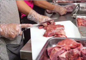  ?? ATHENA ZELANDONII ?? Employees prepare halal meat at a butcher earlier this year in central Phnom Penh.