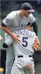  ?? ASSOCIATED PRESS ?? Carlos Gonzalez lifts Nolan Arenado after the Rockies beat the Brewers in 11 innings Sunday. Arenado hit a homer in the top of the 11th.