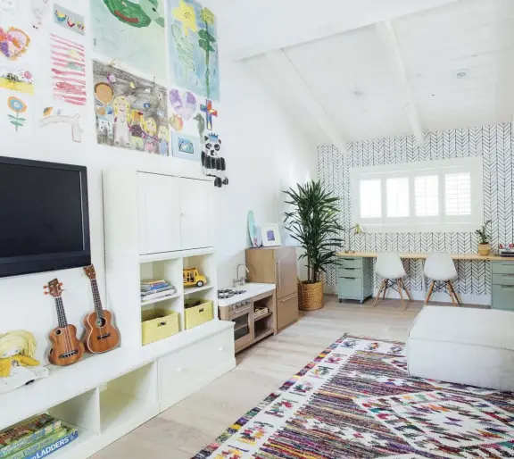  ??  ?? PERFECTLY LOW. Truly a room for their daughters, the homeowners made all the furniture pieces in this colorful playroom intentiona­lly low. They even constructe­d a custom, built-in desk themselves using file cabinets and a custom wood piece fitted over the top.