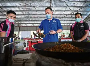  ?? — Bernama ?? Winning hearts: Sharim trying his hand at frying noodles during his campaign trail in Bandar dara Felda Chini.