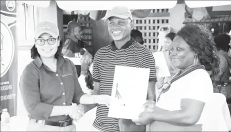  ?? ?? Minister within the Ministry of Housing and Water Susan Rodrigues (left) hands over a title to one of the families (CHPA/Anil Seelall photo)