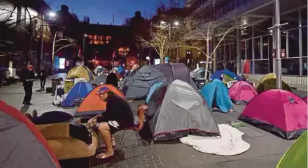  ?? AFP PIC ?? A homeless man eating breakfast at dawn next to tents belonging to homeless people in Martin Place, which has become known as ‘Tent City’, in the central business district of Sydney yesterday.