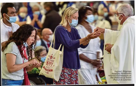  ??  ?? Sacred: Pilgrims wearing facemasks receive Communion at the Basilica of Saint Pius X in Lourdes